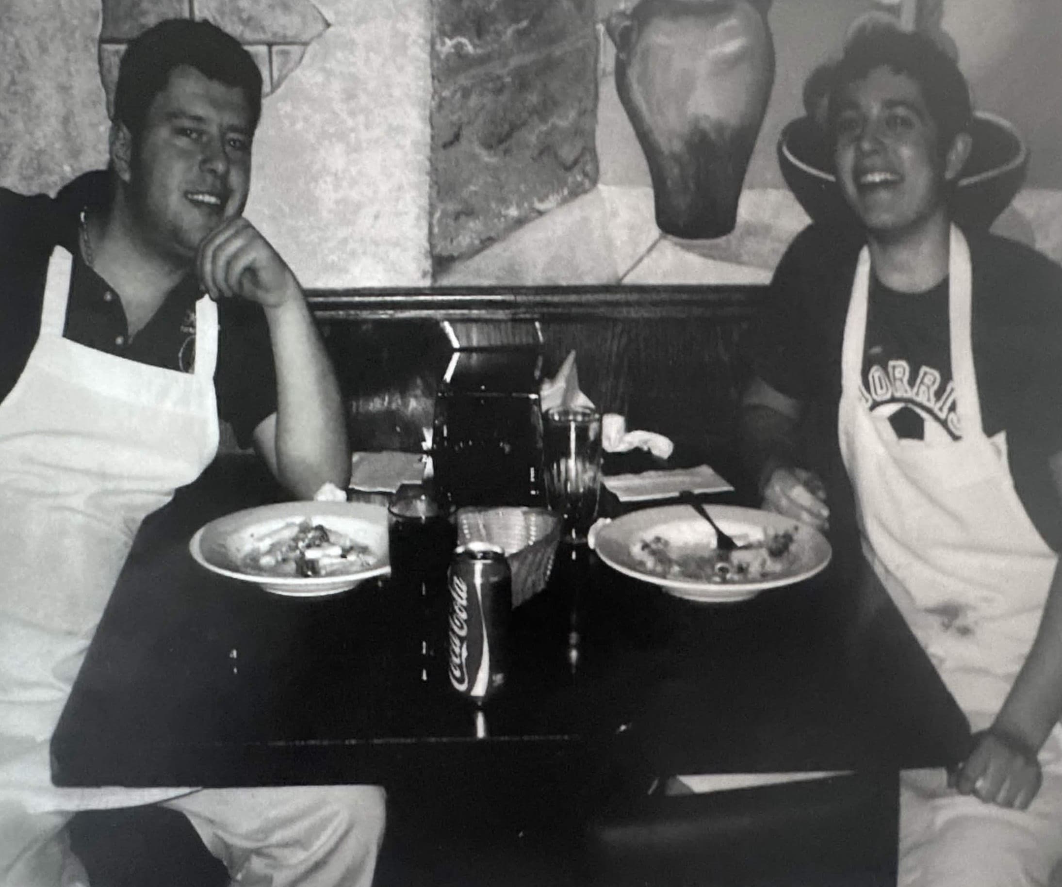 Two young men in aprons at a booth inside Maria's Ristorante.