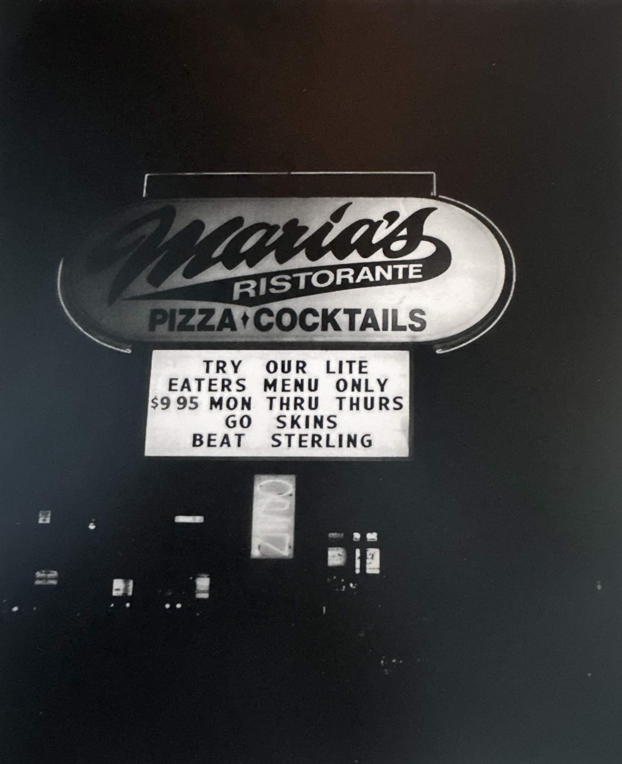Vintage Maria's Ristorante road sign at night.