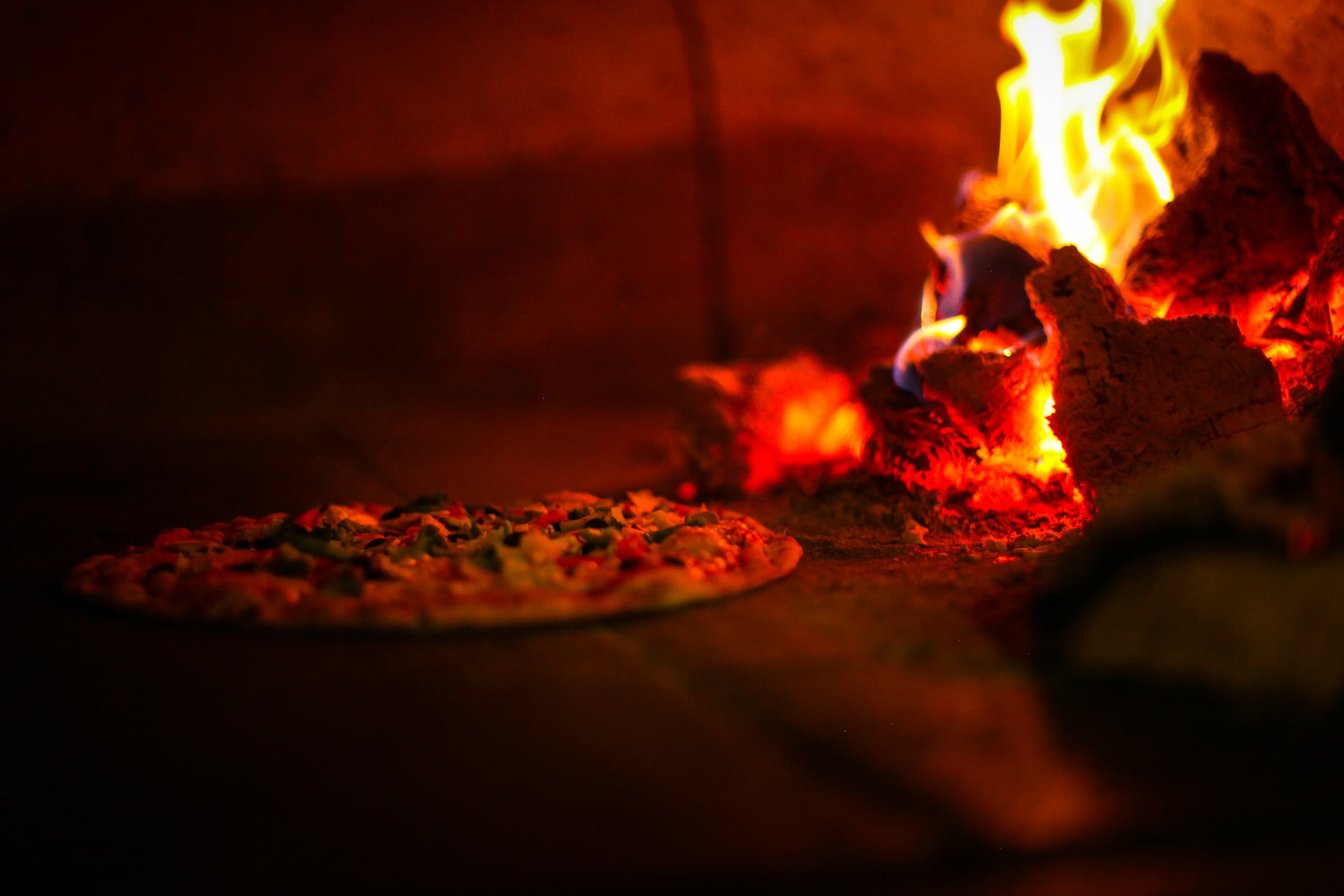 Fresh pizza baking in a wood-fired brick oven