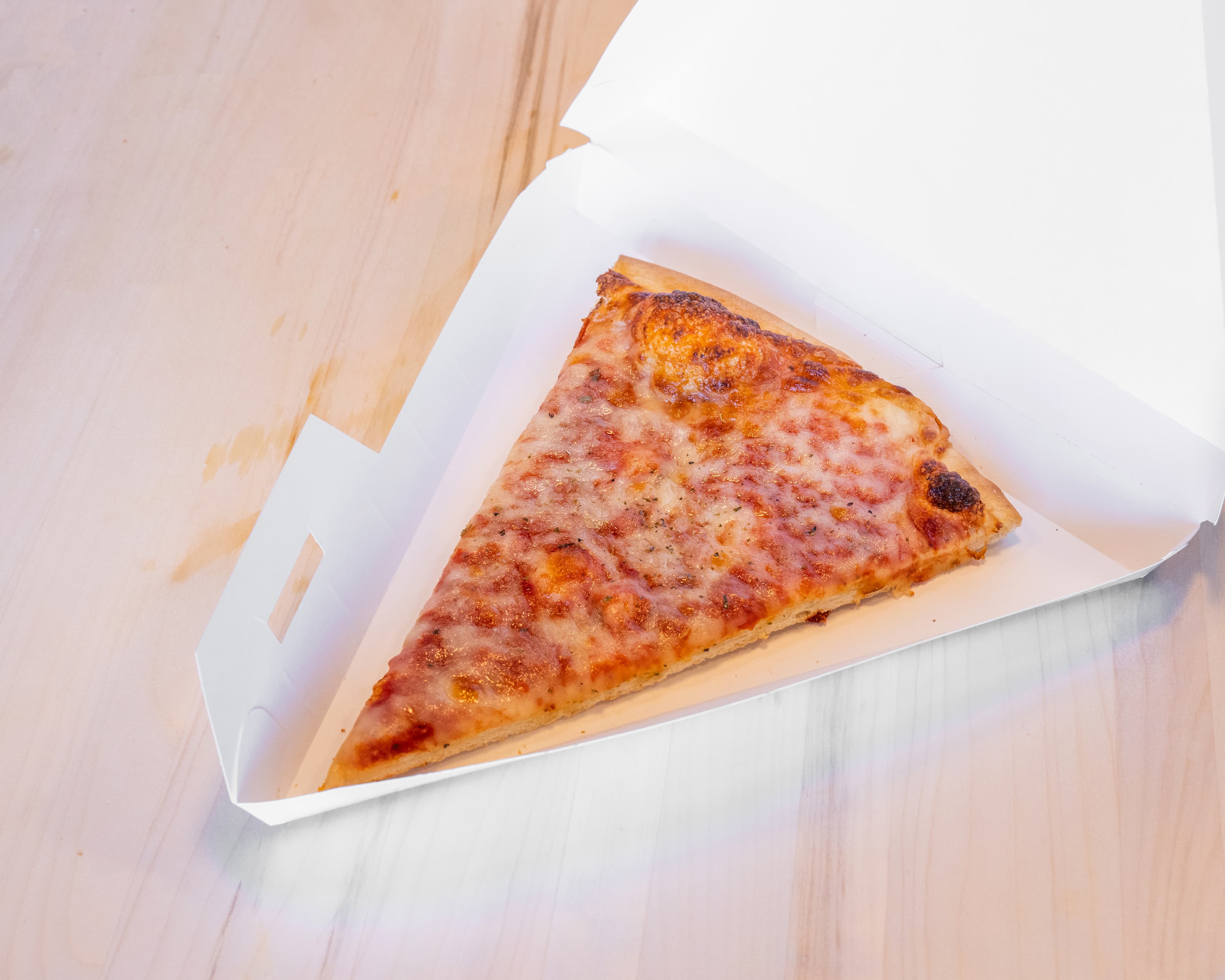 Cheese pizza slice in a takeout box
