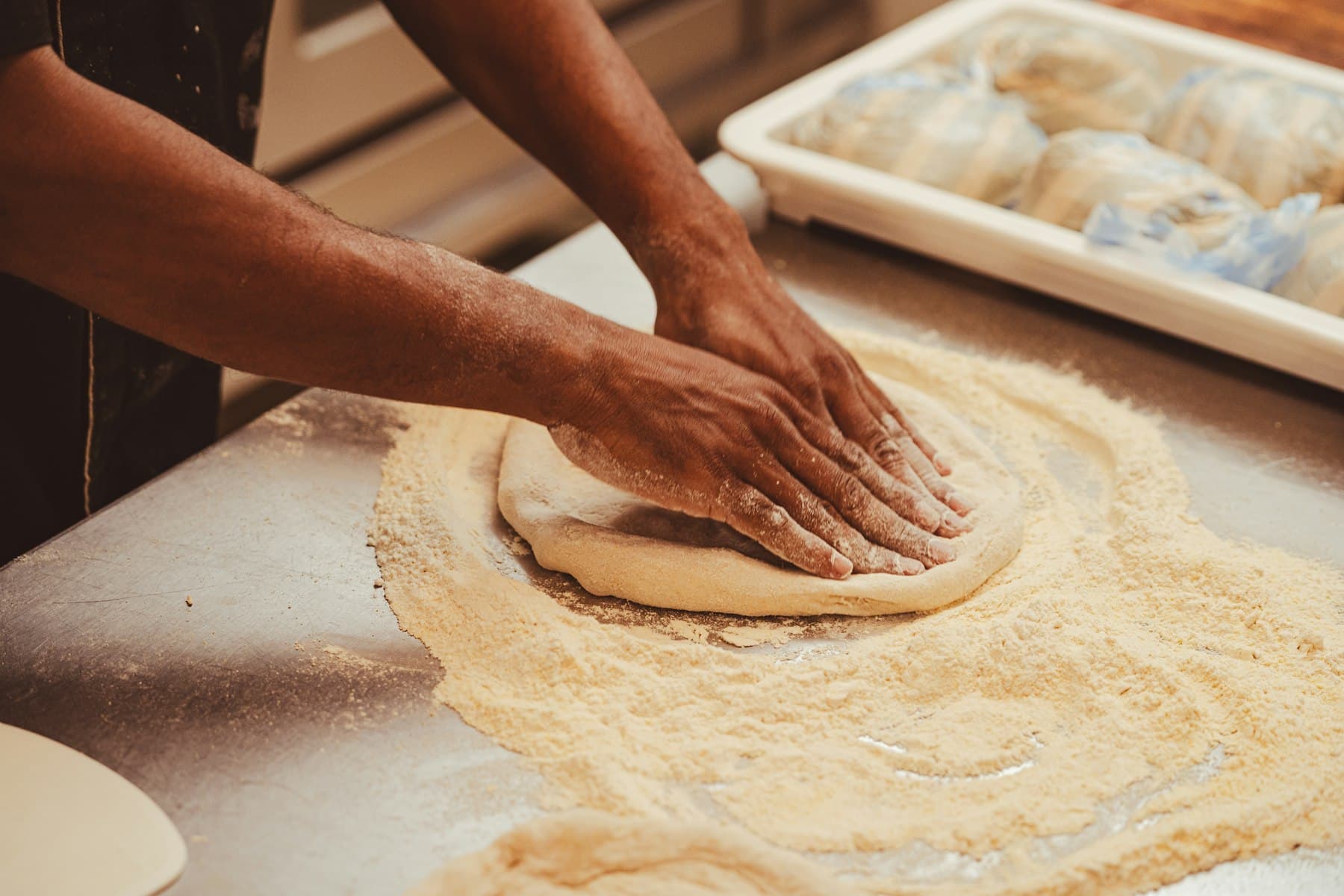Hands shaping pizza dough on a wooden counter
